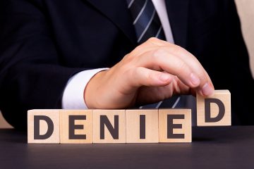 Suit-clad figure placing the letter 'D' to complete "Denied". As a reference to the need for management of complex claim denials.